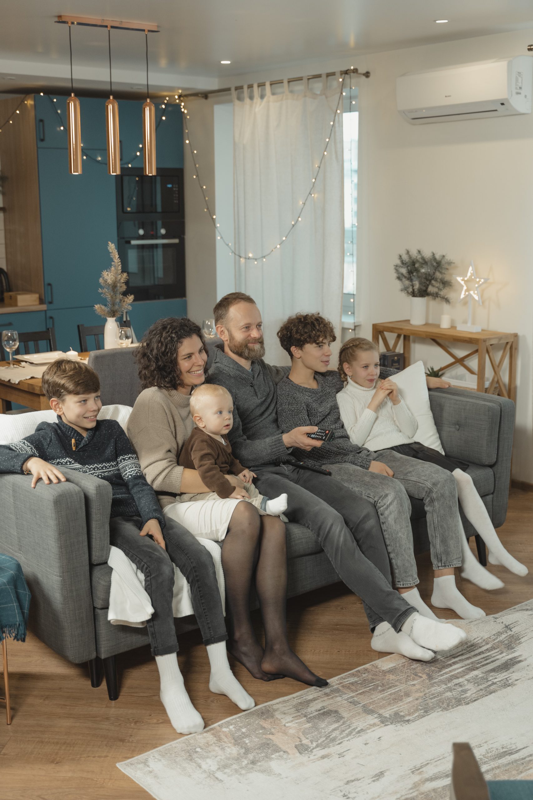 Familie mit großen und kleinen Kindern und Eltern sitzt gemeinsam auf dem Sofa